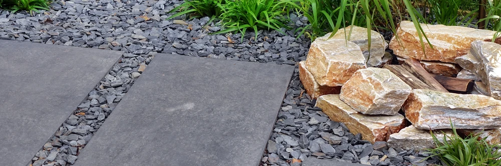 Modern garden path with large stone pavers, gray gravel, and stacked natural rocks in a landscaped outdoor space in Round Rock TX.